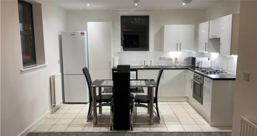 eine Küche mit einem Tisch mit Stühlen und einem Kühlschrank in der Unterkunft ARIEL LUXURY APARTMENT in London