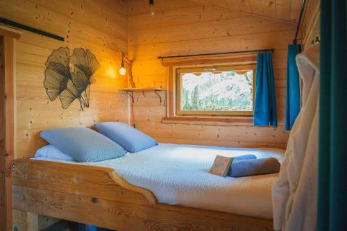 a bed in a log cabin with a window at Cabane Chalet avec spa privatif in Charnay