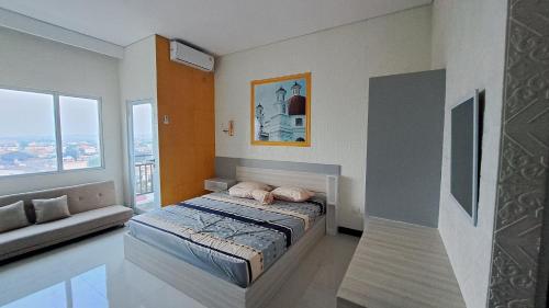 a bedroom with a bed and a couch in it at Apartemen Sentraland Semarang in Semarang