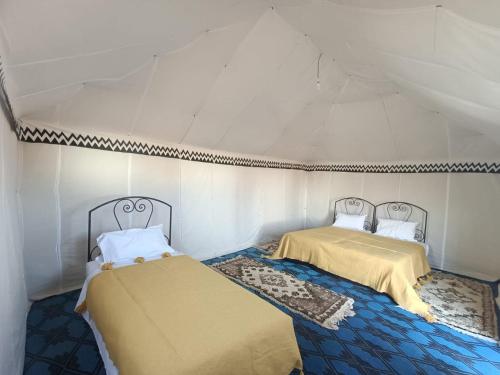a room with two beds in a tent at Zagora Desert Camp in Boikhlal