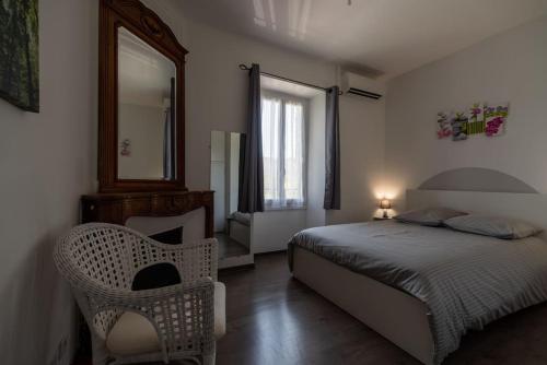1 dormitorio con cama, espejo y silla en Gite Oustalet avec piscine & SPA en Générargues