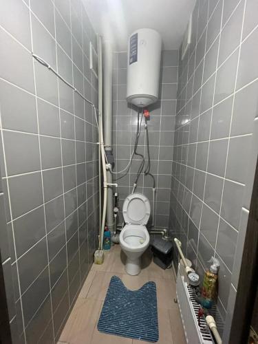 a bathroom with a toilet in a tiled room at Квартира in Karagandy