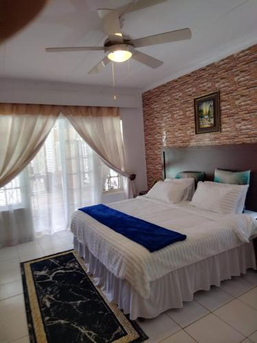 a bedroom with a large bed with a ceiling fan at Comrades Oasis Guest House in Pietermaritzburg