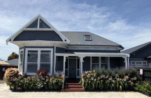 a blue house with flowers in front of it at City Centre Superior Villa 3 large Double bedrooms in Christchurch