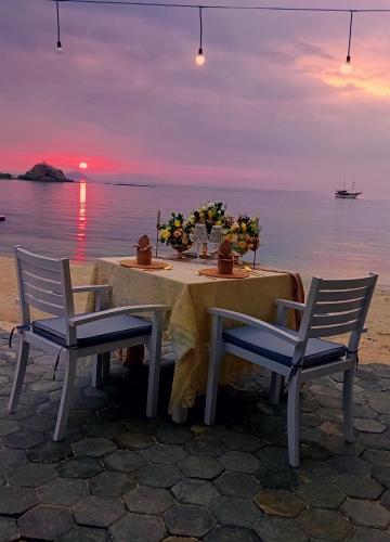 a table with a flower arrangement on the beach at Sylvia Hotel & Resort Komodo in Labuan Bajo
