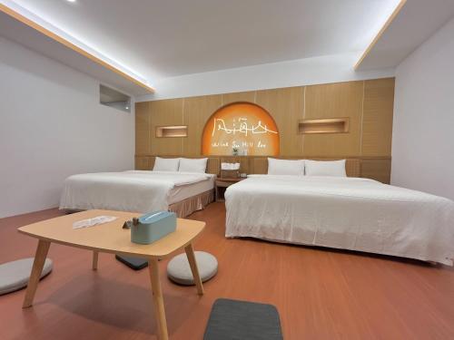 a hotel room with two beds and a table at Wind Sea Hill Inn in Hengchun South Gate