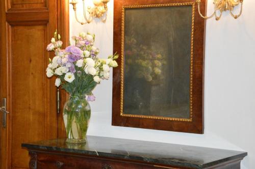 a vase of flowers on a table next to a painting at Villa Gini in Pisa