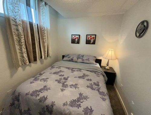 a bedroom with a bed and a table with a lamp at Brand New One Bedroom Suite in Calgary