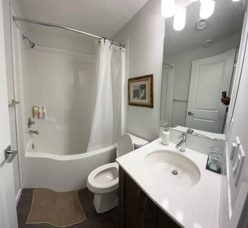 a white bathroom with a sink and a toilet at Brand New One Bedroom Suite in Calgary