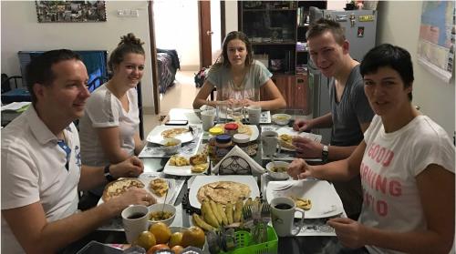 un grupo de personas sentadas alrededor de una mesa comiendo comida en Golpata Bed & Breakfast, en Dhaka