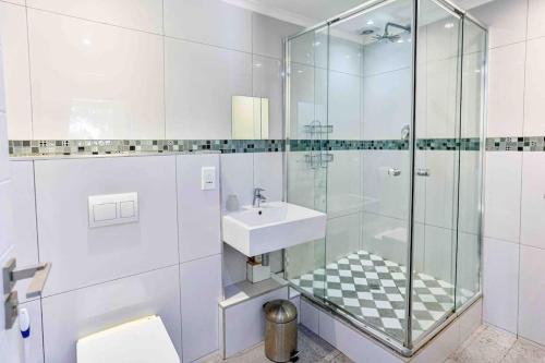 a bathroom with a glass shower and a sink at Seaside 96 - Family only in Ballito