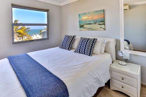 a bedroom with a white bed with blue pillows at Seaside 96 - Family only in Ballito