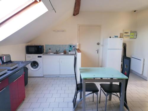 une cuisine avec une table et un réfrigérateur dans l'établissement Appartement climatisé avec parking privé à Doué la fontaine, à Doué-la-Fontaine