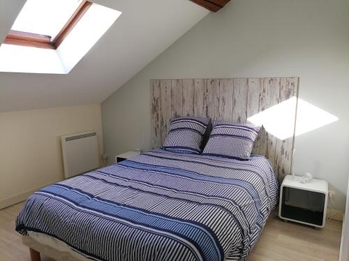 1 dormitorio con 1 cama con manta de rayas azul y blanco en Appartement climatisé avec parking privé à Doué la fontaine, en Doué-la-Fontaine