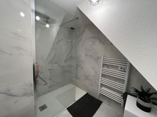 La salle de bains est pourvue de murs en marbre blanc et d'une douche à l'italienne. dans l'établissement Location de villa numéro 3 rénovée en résidence, au Barcarès