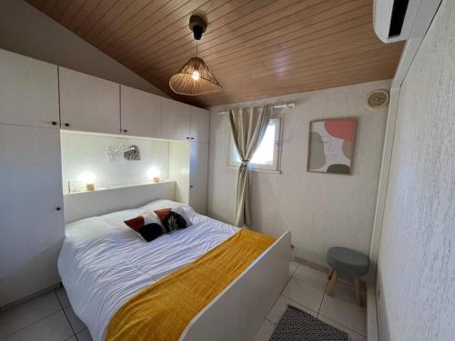 une chambre avec un grand lit blanc avec une fenêtre dans l'établissement Location de villa numéro 3 rénovée en résidence, au Barcarès