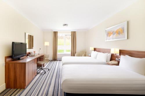 a hotel room with two beds and a flat screen tv at Holiday Inn Leeds Brighouse by IHG in Brighouse