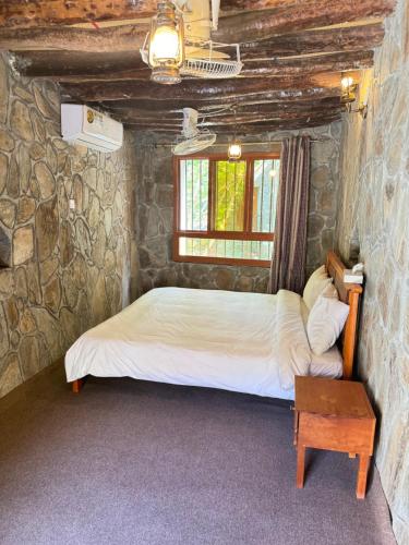 1 dormitorio con 1 cama en una pared de piedra en bait bimah travel lodge en Bīmah
