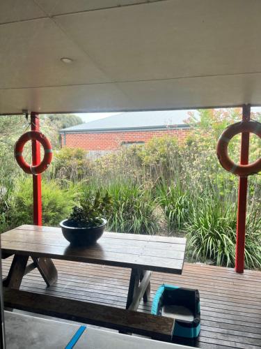 a table on a deck with a bowl on it at Beautiful, Cosy and Quiet in Cape Paterson