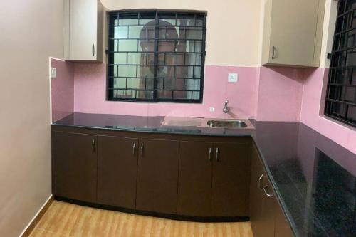 cocina con fregadero y pared rosa en Luxurious 3 BHK flat in Kottayam, en Kottayam