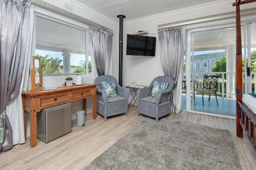 a living room with a desk and two chairs at Oude Schuur Boutique Guesthouse in Hermanus