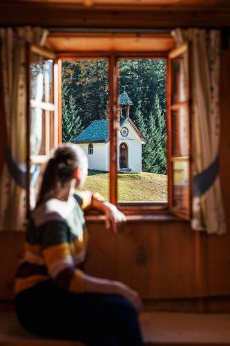 a woman looking out of a window at a church at Ferienhaus Knor in Umhausen