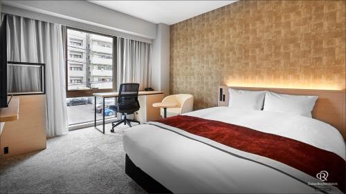 松山市にあるダイワロイネットホテル松山の大きなベッドとデスクが備わるホテルルームです。