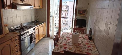 een keuken met een tafel, een fornuis en een wastafel bij Avellino camera matrimoniale CENTRALISSIMA in Avellino