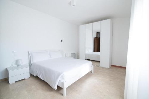 a white bedroom with a white bed and a mirror at Residenza Corso Palladio 159 in Vicenza
