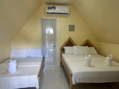 two beds in a small room with white sheets at Dwarf Guest House in Siquijor