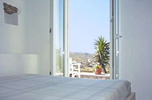 a bedroom with a bed and a large window at Mykonos Love Nest in Ano Mera