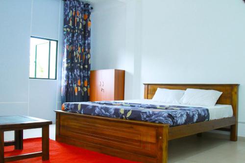 a bedroom with a wooden bed with a blue wall at villa surendra in Weligama