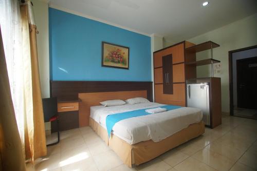 a bedroom with a large bed and a refrigerator at Pineapple Mansion Guest House Solo in Bonorejo