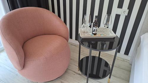 a pink chair next to a side table with wine glasses at Apartment Kampenwand in Aschau im Chiemgau