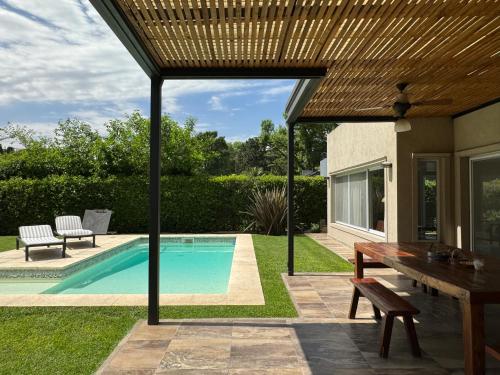 un patio con una mesa y una piscina en Divina casa con parque pileta en mini barrio cerrado. en Del Viso