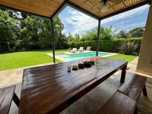 una mesa de madera en un patio trasero con piscina en Divina casa con parque pileta en mini barrio cerrado. en Del Viso