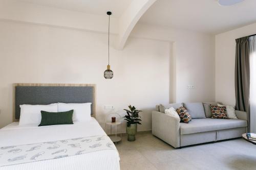 a white bedroom with a bed and a couch at Limeria studios & maisonettes in Parga