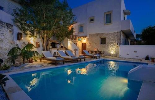 une villa avec une piscine la nuit dans l'établissement Holiday Apartment Agapi, à Kamilárion