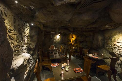 a restaurant in a cave with tables and chairs at The President Hotel in Hubli