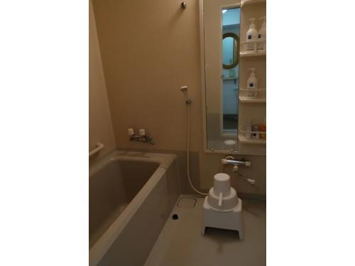 a bathroom with a tub and a sink and a mirror at Asahikawa Henshushitsu - Vacation STAY 13647 in Asahikawa