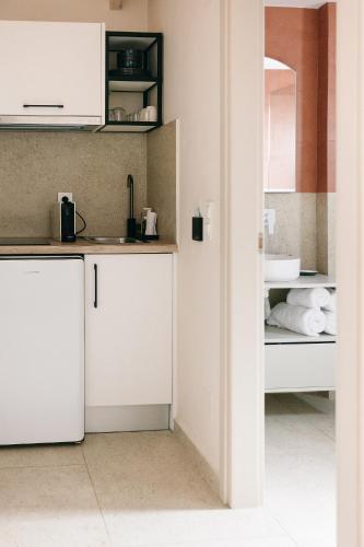 a kitchen with white cabinets and a sink at Limeria studios & maisonettes in Parga