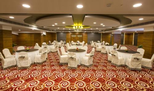 a banquet hall with round tables and white chairs at The President Hotel in Hubli