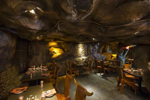 a restaurant in a cave with tables and chairs at The President Hotel in Hubli