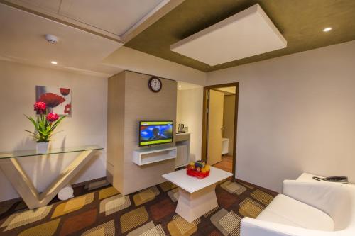 a living room with a white couch and a television at The President Hotel in Hubli