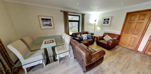 a living room with leather furniture and a piano at Osprey Lodge with river and mountain view in Crianlarich
