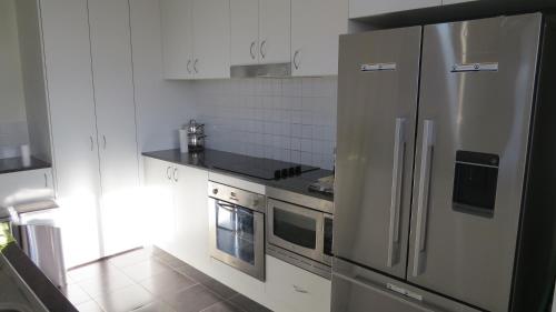 Il comprend une cuisine équipée d'un réfrigérateur en acier inoxydable et d'une cuisinière. dans l'établissement GREENWAY WATERS Apartments, à Tuggeranong