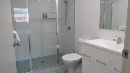 a bathroom with a shower and a toilet and a sink at GREENWAY WATERS Apartments in Tuggeranong