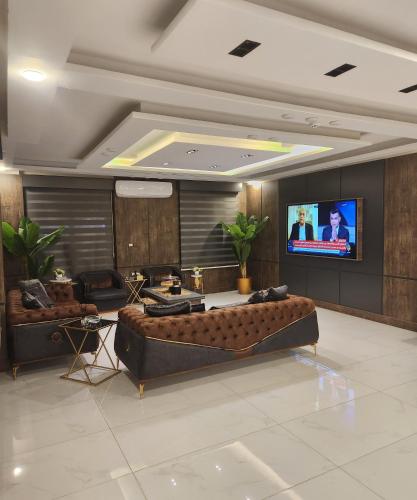 رويال جروب اربد Royal Group Hotel في إربد: غرفة معيشة مع أريكة وتلفزيون بشاشة مسطحة