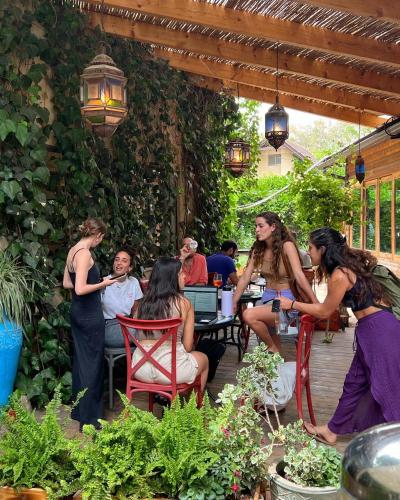 a group of people sitting at a table in a garden at Vitrage Holiday Village and Spa in Bet Hillel