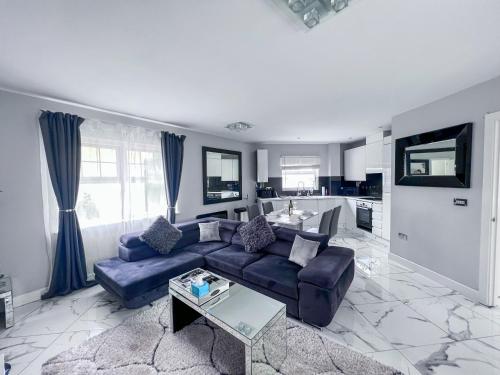 a living room with a blue couch and a kitchen at 2 Double Bedroom Apartment in Edgware, London in Edgware